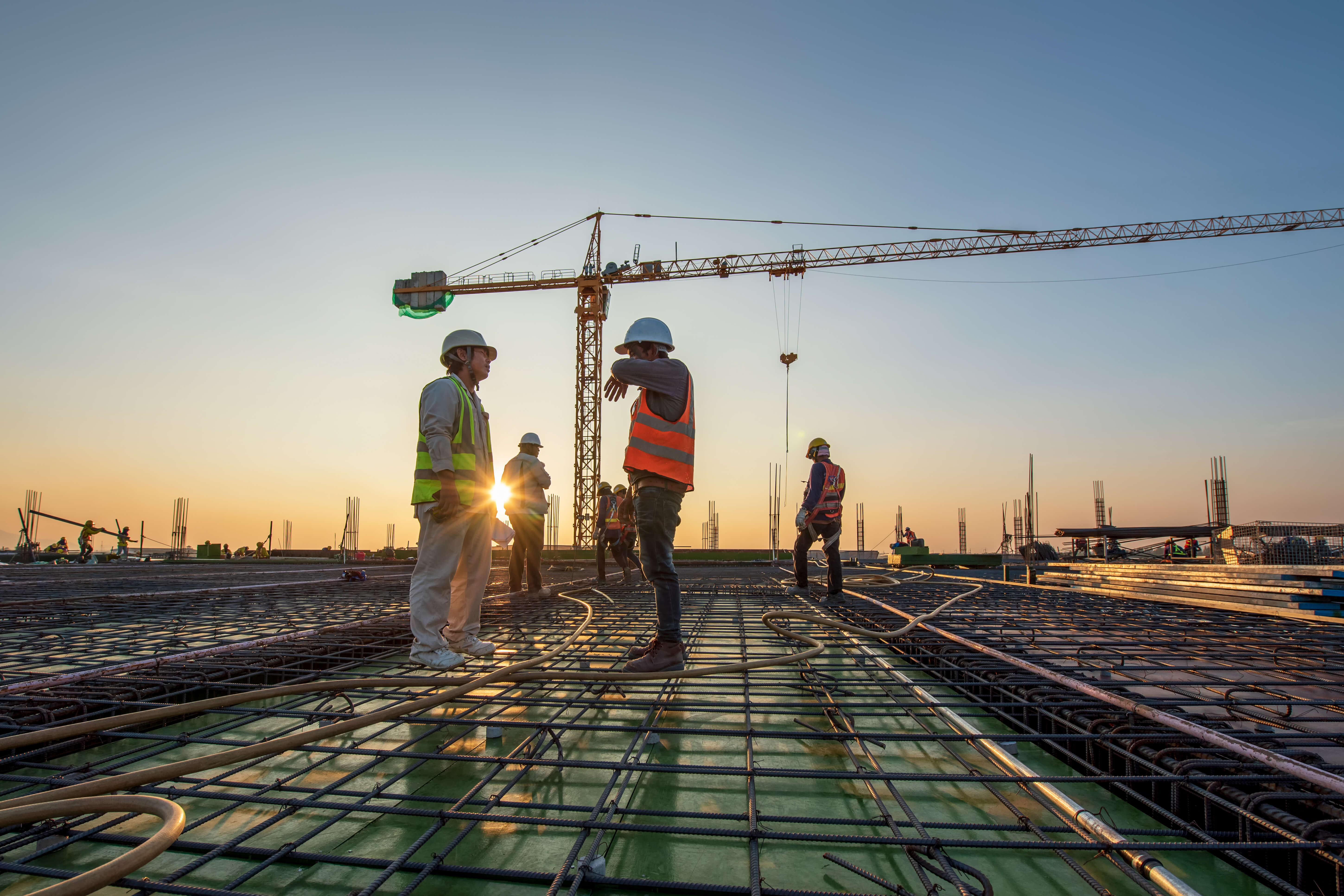 construction workers on a roof with a crane in the background